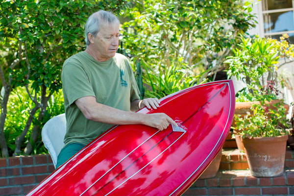 Rich Pavel pointing out his choice logo on a red surfboard
