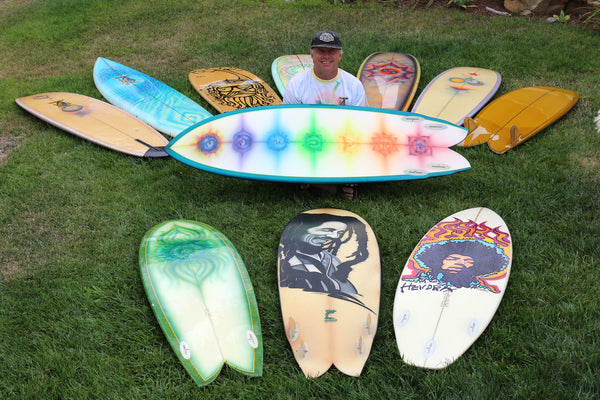 John Frazier sitting with his collection of Rainbow Surfboards 