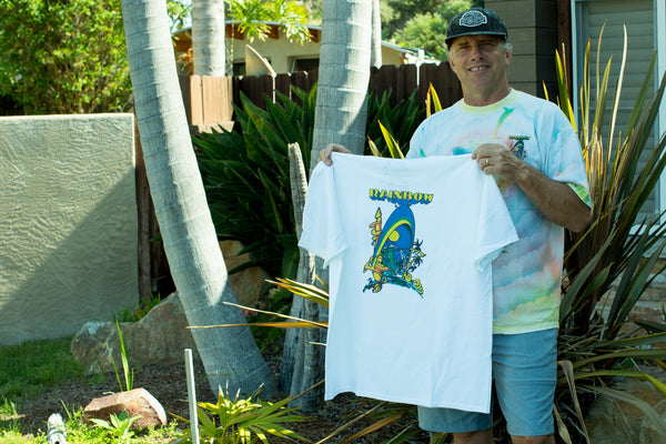 John Frazier standing with his white Rainbow Surfboards t-shirt