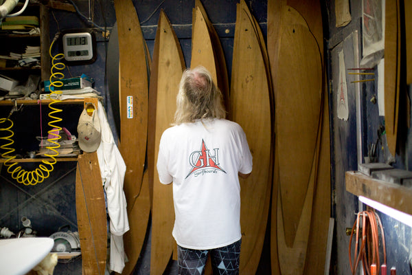 Gary Hanel standing in his surfboard shaping room looking at surfboard templates